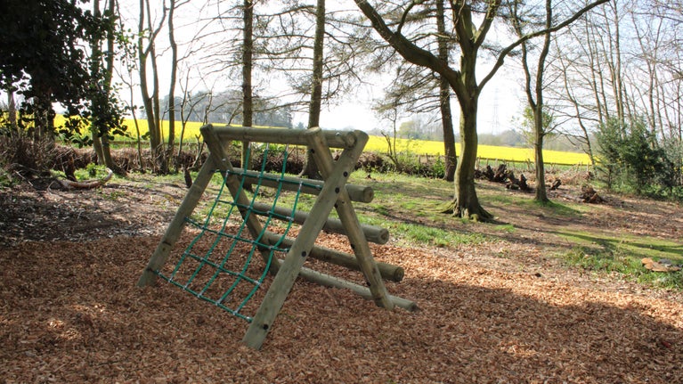 An 'A' shaped climbing frame in the Woodland at Moseley Old Hall, with a rope climb on one side, and wooden ladder on the other.